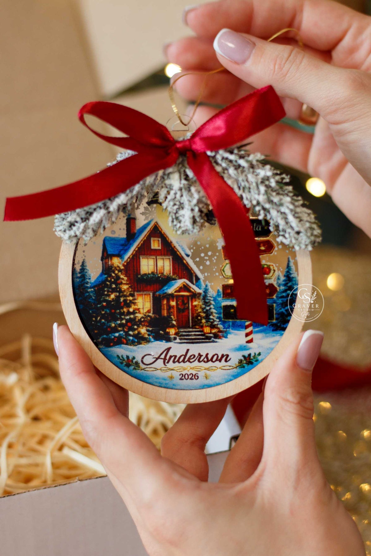 Wooden family name Christmas ornament held in hand against festive lights