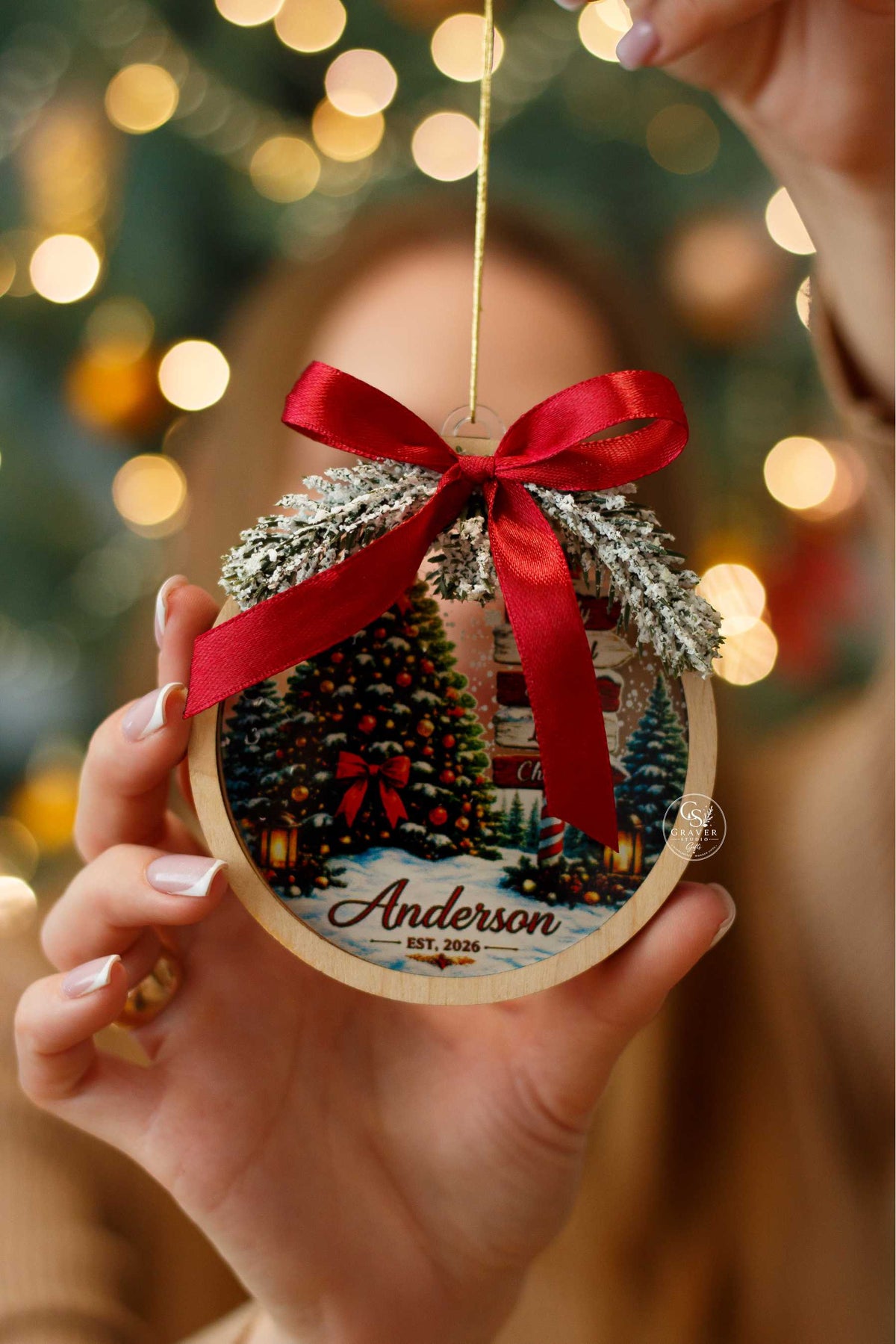 Personalized wooden Christmas ornament with family name, red ribbon and pine greenery